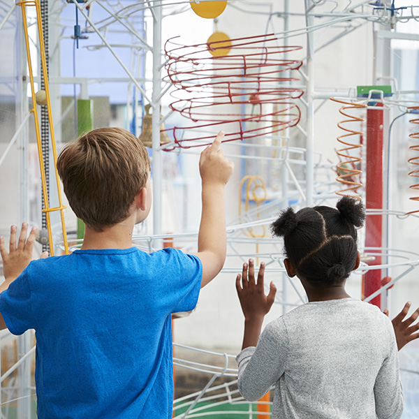 Two kids looking at a science exhibit, back view
