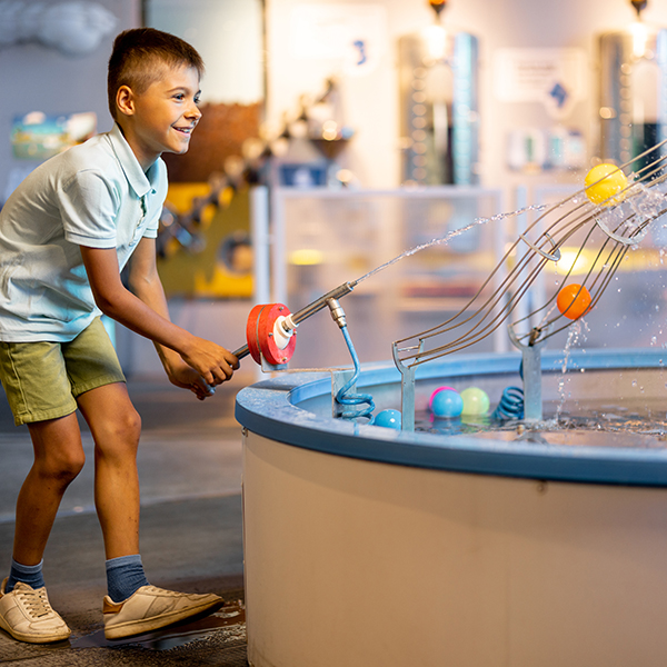 Little boy plays with balls, learning physical phenomena in an interesting way, having fun in a STEAM children's museum with interactive models
